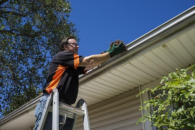 an experienced worker repairing a gutter on a house in Coral Springs